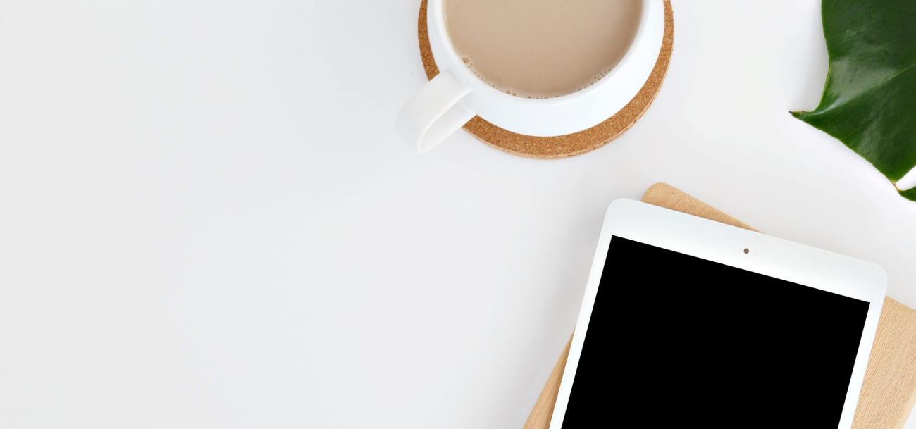 Tablet and a cup of coffee flat on a desk